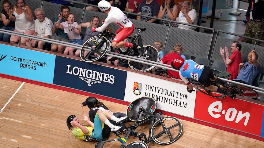 A male track cyclist lands in the crowd with his bike following a crash at the Commonwealth Games.