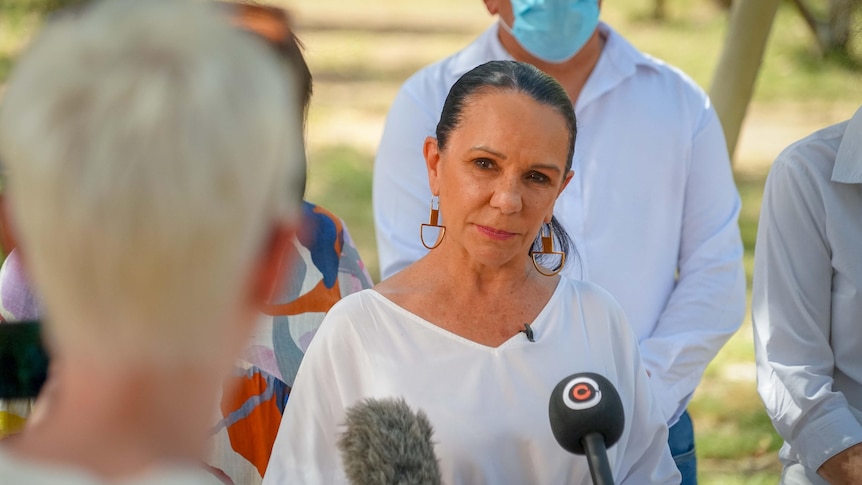 photo of a woman with her hair back in a ponytail wearing a white shirt