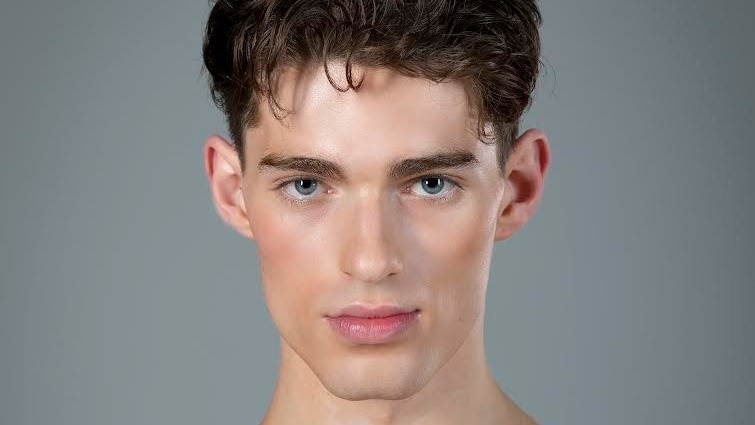 Close up of a chiseled jaw young man wearing stage makeup.
