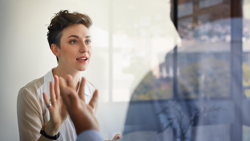 A woman and a man in deep conversation, with their hands raised.