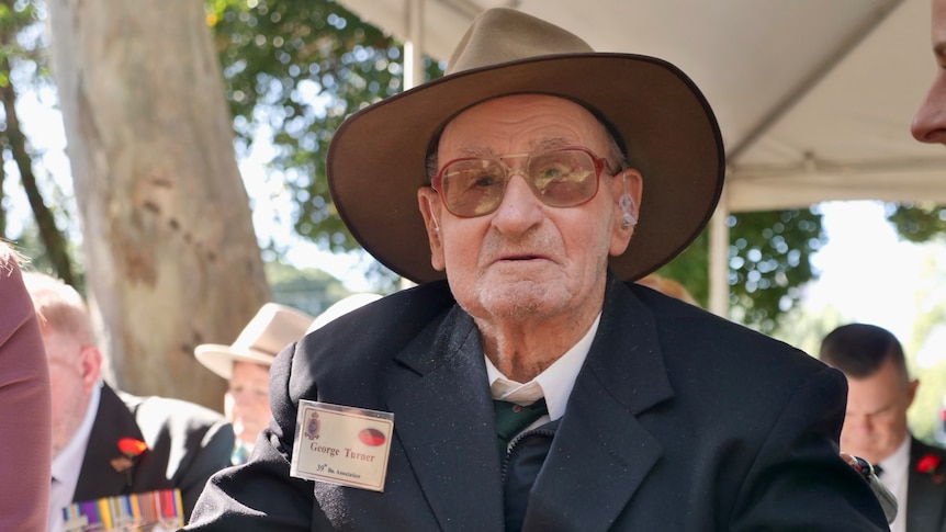 Kokoda veteran, George Turns sits looking forward, wearing his military medals and hatand