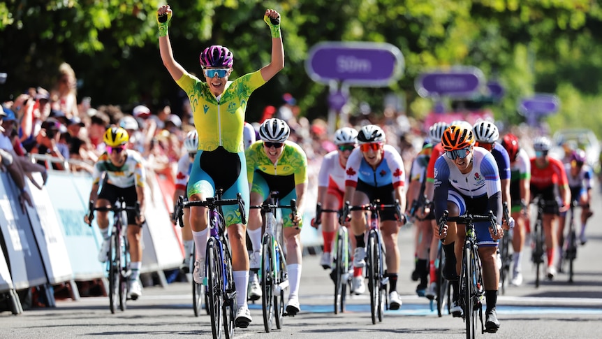 An Australian cyclist raises her arms in triumph as she crosses the finish line in The Commonwealth Games women's road race.