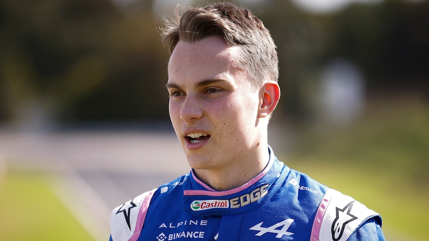 Australia's Oscar Piastri stands wearing his Alpine team driving gear while speaking to media.