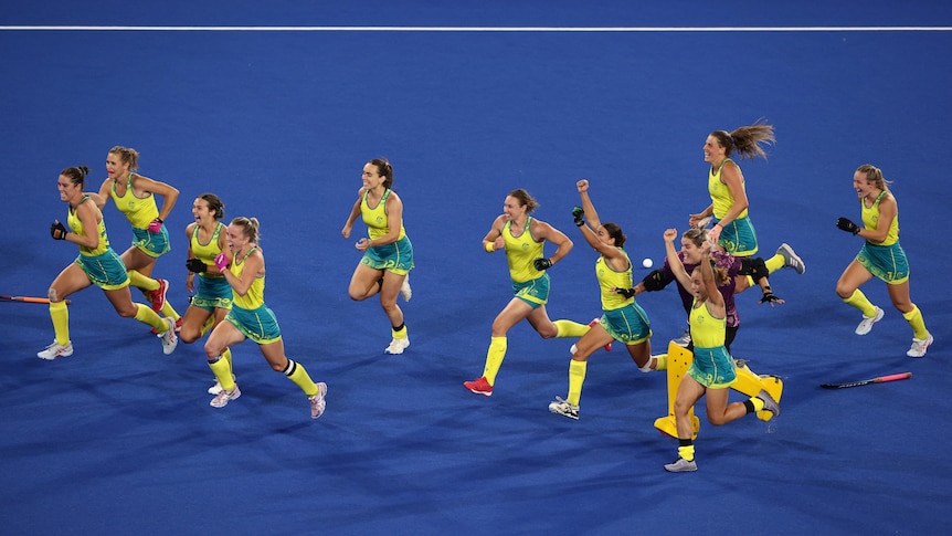 Australia players run forward with their arms in the air and smiles on their faces
