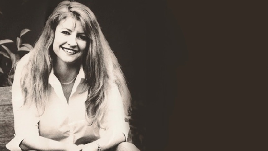 A woman sits down smiling at the camera in a black and white photo