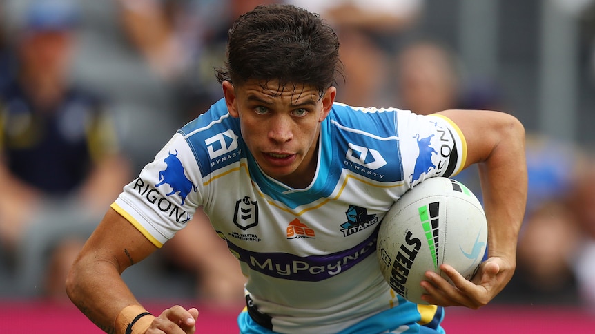 A Gold Coast NRL players runs with the ball.