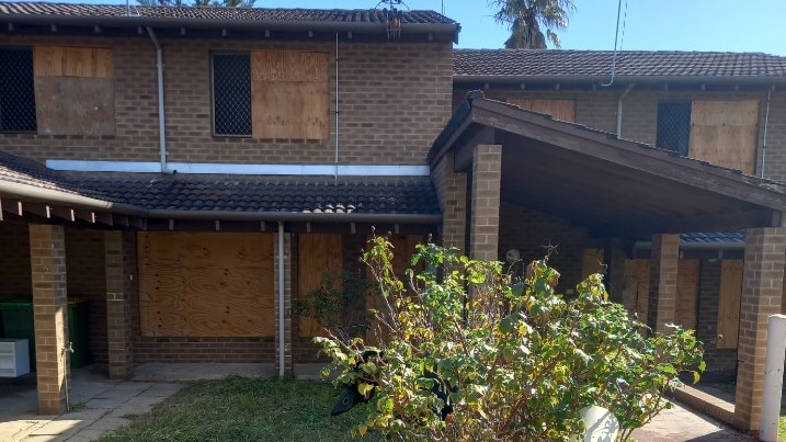 A boarded-up two story house in a suburban area.
