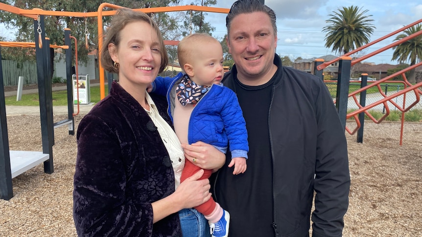 Woman and man with their baby in a playground.