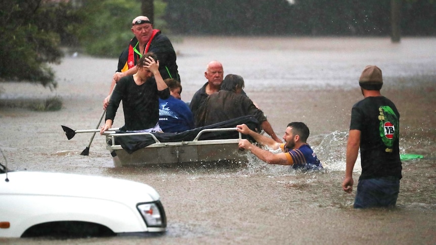 People in a boat rescue another man in the water