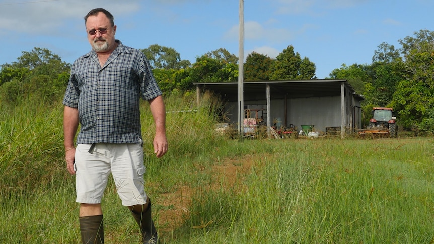 Wide shot of a bearded man walking away from a farm shed