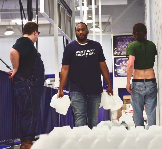Charles Booker carrying jugs of water into an emergency shelter at Letcher County Central High School in flood-ravaged Whitesburg on Saturday