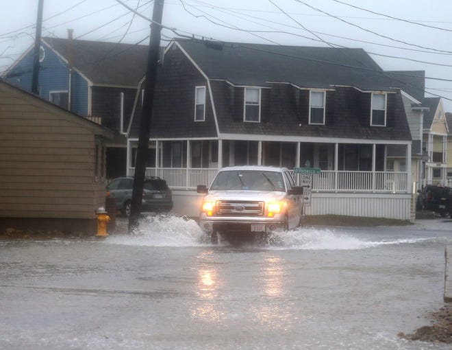 A pickup truck throws a wake during high tide flooding in Scituate, Mass., in October 2021. National Ocean Service officials say such flooding is occurring at least twice as often as it did in 2000.